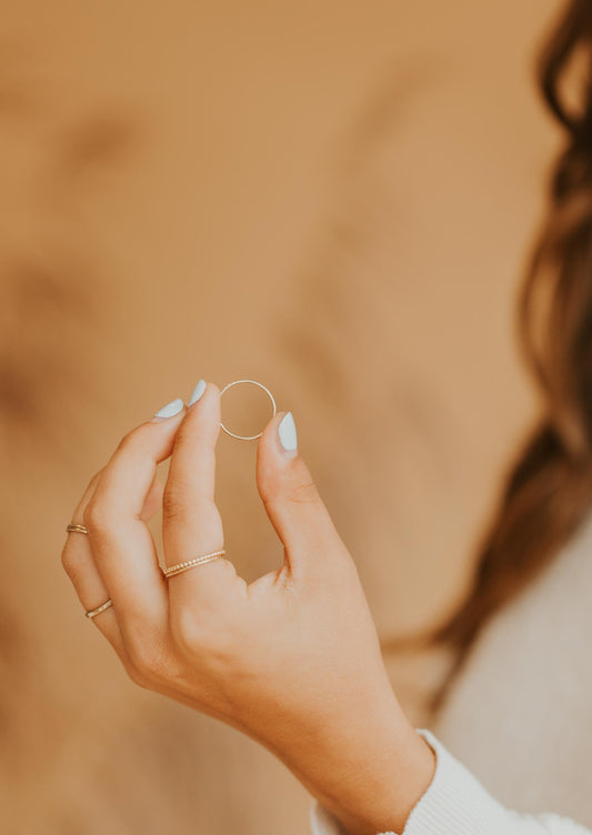 Gold Teeny-Tiny stackable ring being held, styled with Confetti Ring and Aden Band to create a ring stack by Hello Adorn.